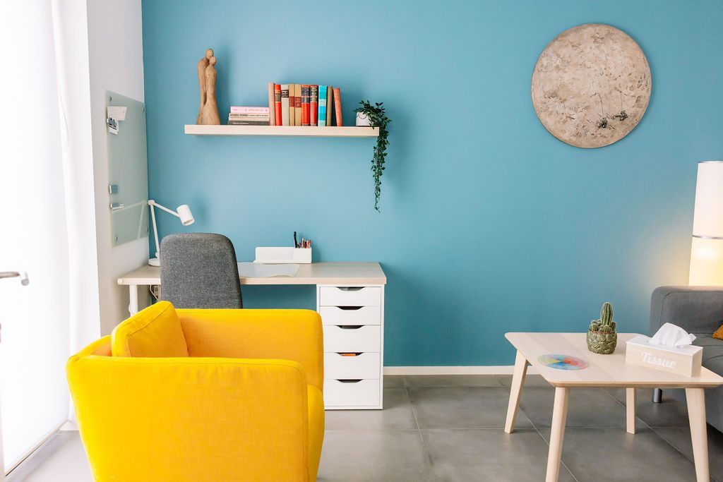 Een rustige werkkamer met gele fauteuil en bureau in de praktijk